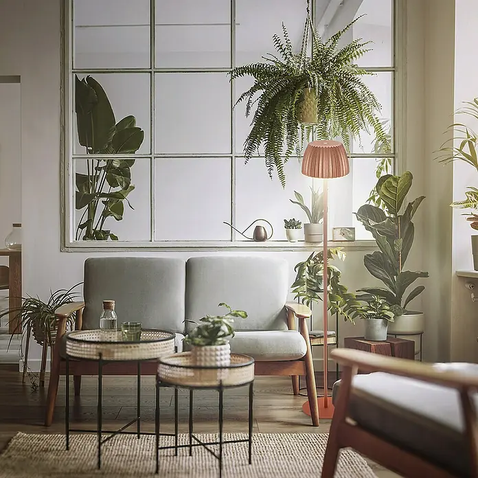 Brilo Riffle Akku-Stehleuchte Maxi - Ø x H: 19 x 124,1 cm, Kupfer, Warmweiß, 4,2 W, IP44 - Einladendes Wohnzimmer mit einem grauen Sofa, Beistelltischen, einer Stehlampe und üppigen Zimmerpflanzen, die eine gemütliche Atmosphäre schaffen.