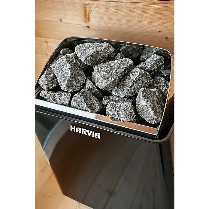 Tuindeco Saunaofen Harvia Trendy XE - 9 kW, Raumheizvermögen: 7 m³ - 13 m³ - Nahaufnahme eines Harvia Saunaofens mit Steinen. Der Ofen ist schwarz und hat einen silbernen Rand.