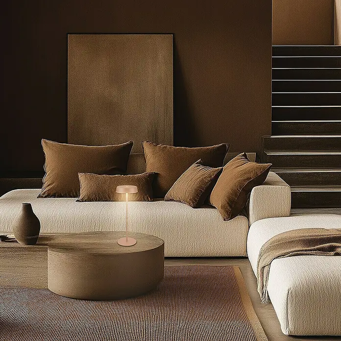 Brilo Akku-Tischleuchte Pala - Ø x H: 13 x 36,5 cm, Coffee, Warmweiß, 2,6 W, IP44 - Eine elegante Szene mit einer modernen Lampe auf einem runden Tisch, umgeben von warmen Brauntönen und Texturen im Raum.