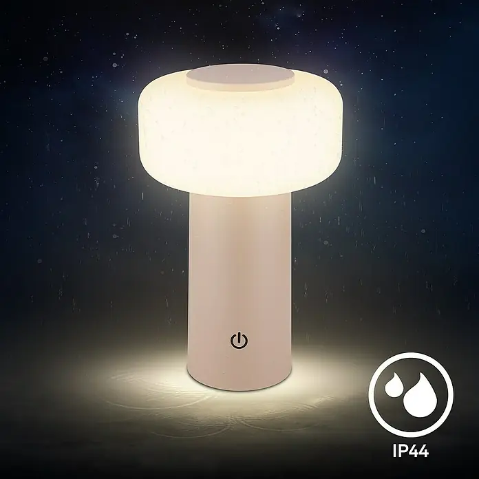 Brilo Akku-Tischleuchte Juna - Ø x H: 13 x 20,5 cm, Beige, Warmweiß, 1,8 W, IP44 - Nahaufnahme einer stilvollen, beigen Tischlampe, die ein warmes Licht ausstrahlt und mit dem IP44-Schutzzeichen für Wasserdichtigkeit versehen ist.