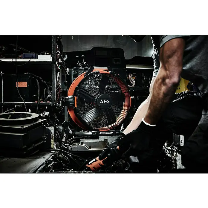AEG Pro 18V Hybrid-Ventilator BDF18-0 - 18 V, Ohne Akku, Schwenkbereich: 210 ° - Ein AEG-Lüfter steht im Mittelpunkt, während ein Mechaniker an einem Motor arbeitet, was die Marke und die Anwendung hervorhebt.