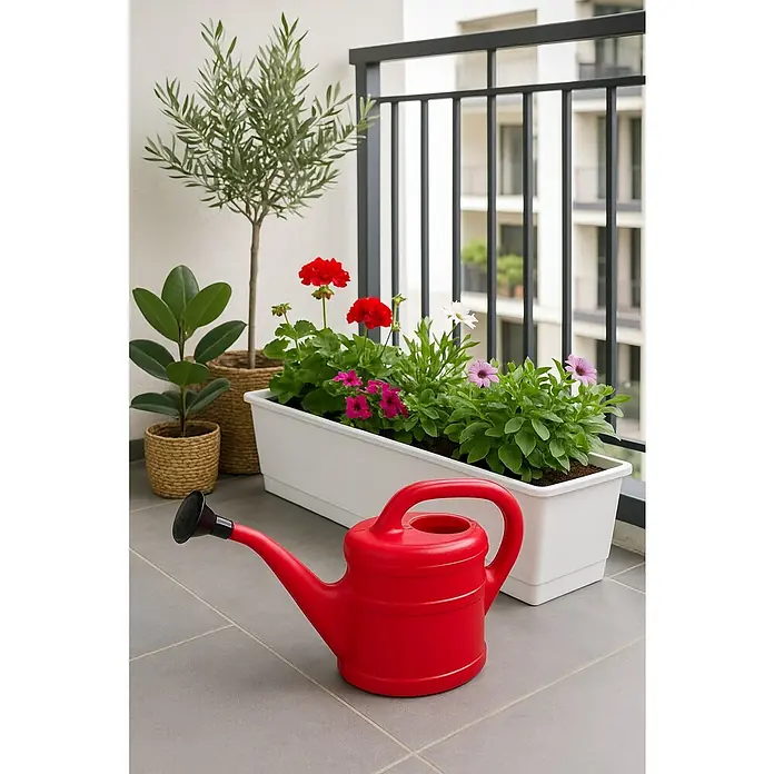 Geli Gießkanne - Rot, 2 l - Nahaufnahme einer roten Gießkanne auf einem Balkon mit Pflanzen. Sie steht vor einem Pflanzgefäß mit bunten Blumen.