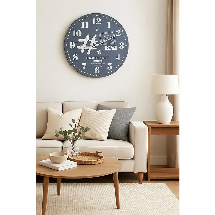 Reloj de pared Elisabeth street - Diámetro: 55 cm, Multicolor - Idea de diseño de interiores con una esfera de reloj azul en la pared sobre un sofá con cojines claros y una mesa redonda de madera.