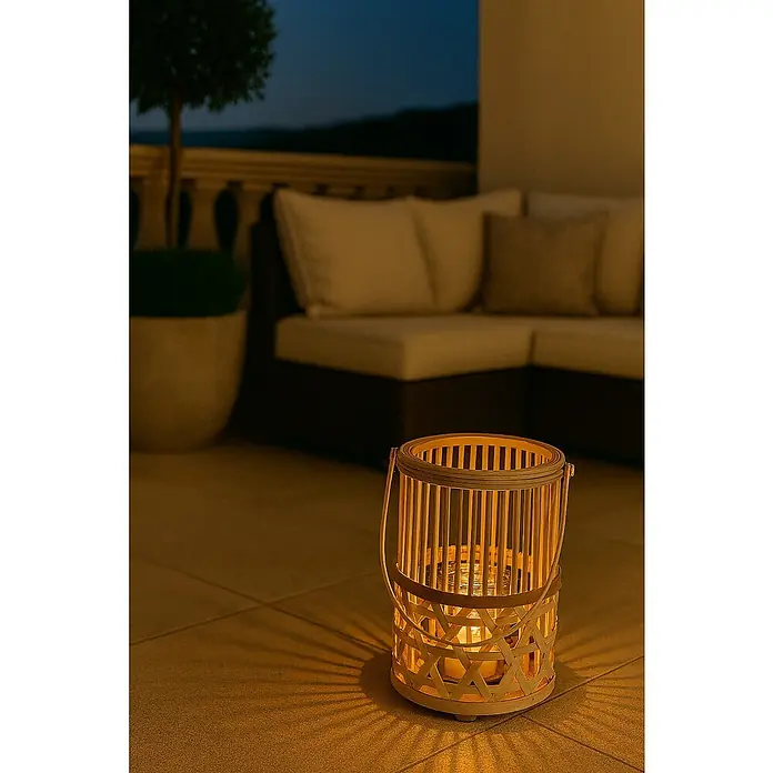 Farolillo Victor - Ø x Al: 21 x 40 cm, Natural/Gris - Imagen atmosférica de una linterna que proyecta un brillo cálido en un patio al aire libre, con muebles suaves al fondo.