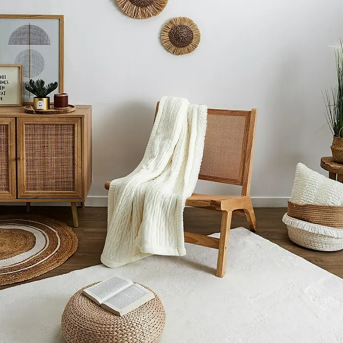 Home Deco Factory Bali Silla - Madera de Hevea, Marrón, Con ratán trenzado - Una manta de punto color crema está casualmente sobre una silla de madera, creando un ambiente acogedor y atractivo.
