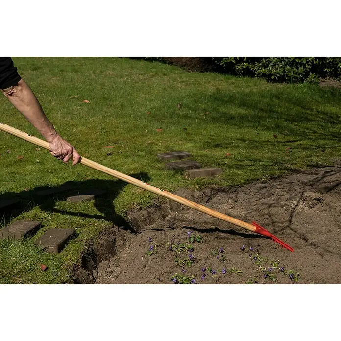 Gardol Gartenrechen - Arbeitsbreite: 35 cm, Anzahl Zinken: 14, Langstiel - Auf dem Bild ist ein Rechen mit rotem Kopf und Holzstiel zu sehen, der im Garten verwendet wird, um die Erde zu bearbeiten und vorzubereiten.