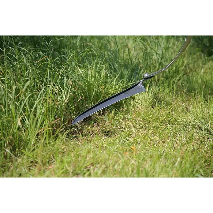 Freund Victoria Klappsense - Länge: 138 cm, Stahlrohr-Sensenbaum - Nahaufnahme einer scharfen Grasschneideklinge im Gras, ein Werkzeug für die Gartenarbeit. Es ist ideal zum Trimmen von Gras und kleinen Büschen.
