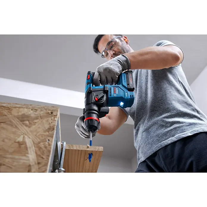 Bosch Professional AMPShare 18V Juego de máquinas - 18 V, 1 batería, 2 Ah, 4 pzs. - Primer plano de un hombre usando un taladro inalámbrico Bosch Professional para perforar una tabla de madera.