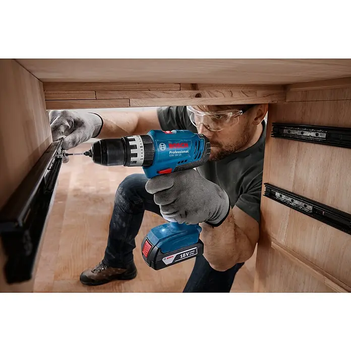 Bosch Professional AMPShare 18V Juego de máquinas - 18 V, 1 batería, 2 Ah, 4 pzs. - Hombre fijando guías de cajón con un taladro atornillador a batería Bosch Professional GSB 18V-25. La herramienta es robusta y fiable.