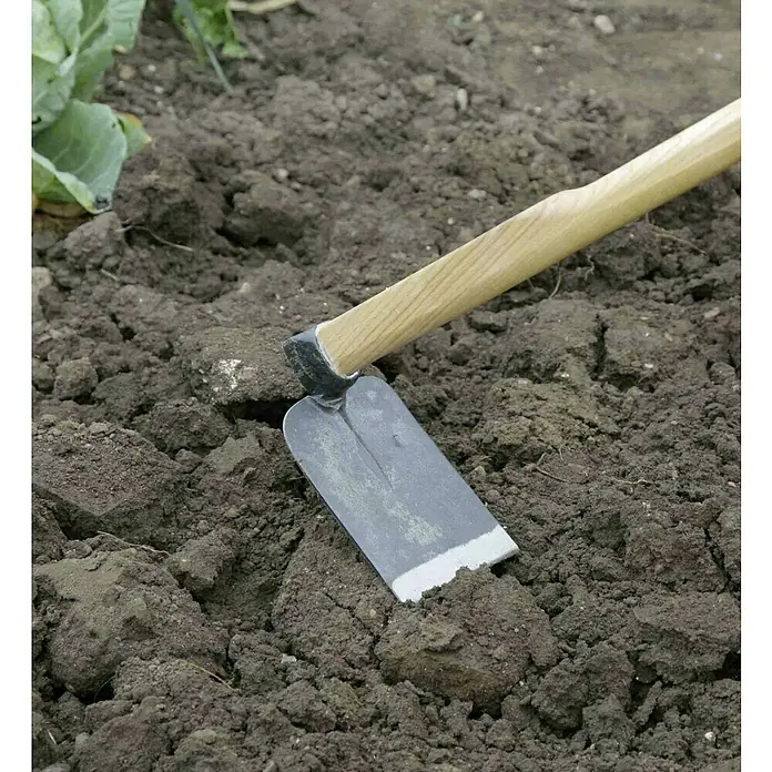 Gardol Rheinische Hacke - Arbeitsbreite: 11 cm, Geschmiedet, Langstiel - Nahaufnahme einer Gartenhacke mit Holzgriff, die auf lockerer Erde liegt. Ideal für Gartenarbeit und Gemüseanbau.