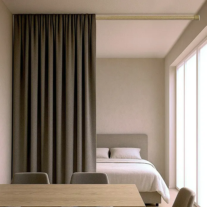Barra para cortinas extensible multiusos - Metal, Madera, Longitud regulable: 70 cm - 120 cm - Cortina gris que divide una habitación, con una mesa de madera y sillas en primer plano y una cama al fondo.