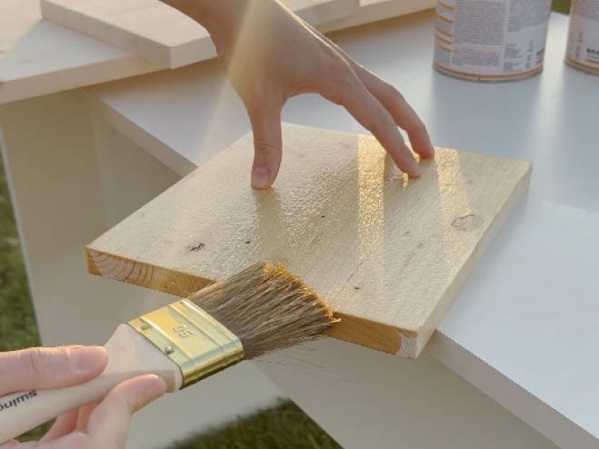 Ein Holzplatte wird mit einer transparenten Lasur angestrichen