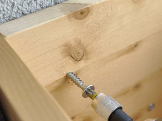 Das Fensterbeet aus Holz wird an die Hausmauer angeschraubt