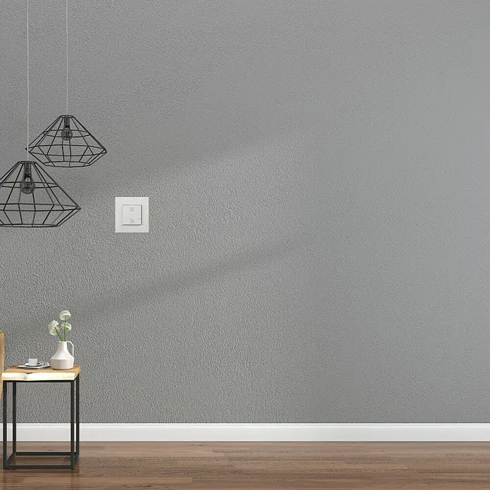 Legrand Valena Next with Netatmo Conmutador Entrar/salir - Blanco, Montaje en la pared, 16 A - Interior elegante con lámpara minimalista y mesa elegante. La pared gris proporciona un fondo moderno.