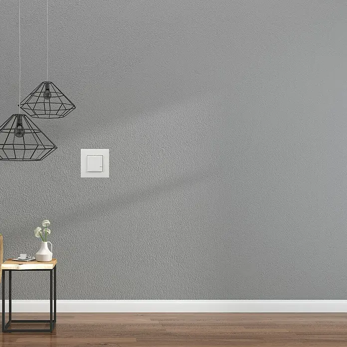 Legrand Valena Next with Netatmo Conmutador On/Off - Blanco, Montaje en la pared - Primer plano de un interruptor de pared blanco y moderno en una habitación elegante con fondo gris y decoración minimalista.