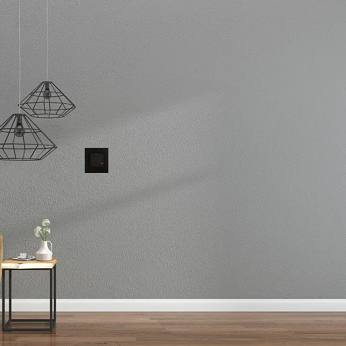 Legrand Valena Next with Netatmo Conmutador On/Off - Negro, Mate, Montaje en la pared - Primer plano de una mesa minimalista con jarrón decorativo y lámparas elegantes contra una pared gris.