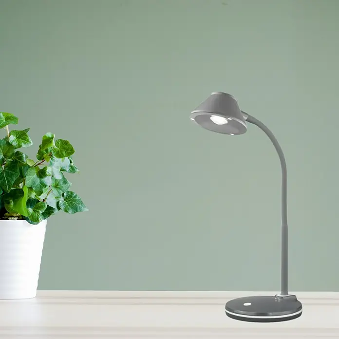 Reality Leuchten Lámpara de sobremesa LED Berry - 3,2 W, Titanio, Blanco cálido - Una lámpara de escritorio gris con luz LED está sobre una mesa junto a una planta verde en una maceta blanca.