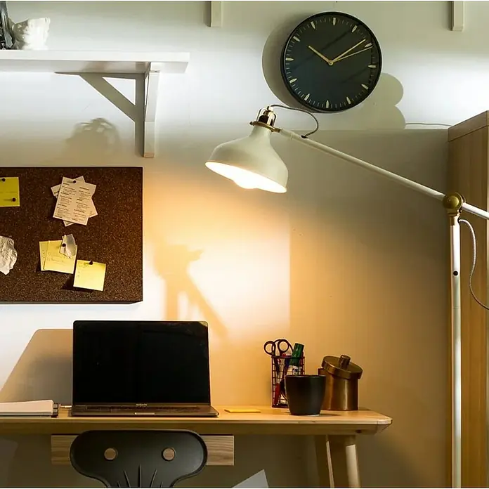 Garza Bombilla LED inteligente Pack - GU10, Blanco cálido, 400 lm, 4,5 W - Un espacio de trabajo moderno con un portátil, una lámpara y un reloj de pared, que combina funcionalidad y estética.