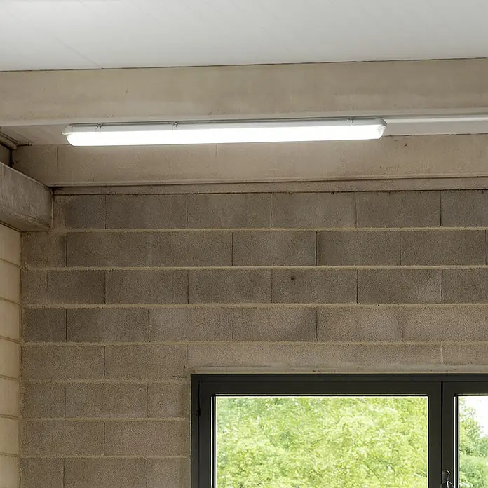 Eglo Feuchtraumleuchte Expert Basic - 23 W, Grau, Neutralweiß, 156 cm, 7,3 cm - Nahaufnahme einer LED-Feuchtraumleuchte, die an einer Betondecke montiert ist und helles Licht in einem Raum mit Betonmauerwerk spendet.