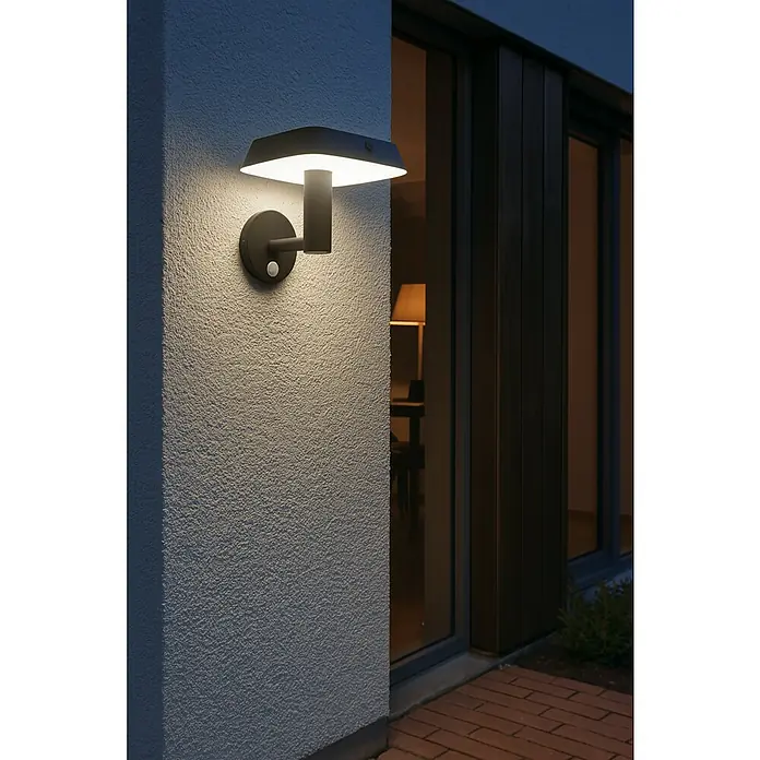 Eglo Aplique solar LED para exterior Dreoli - 8 W, Plástico, Blanco cálido, Negro - Moderna lámpara de pared exterior con sensor de movimiento ilumina la pared de una casa. La lámpara es negra y emite una luz cálida y acogedora.