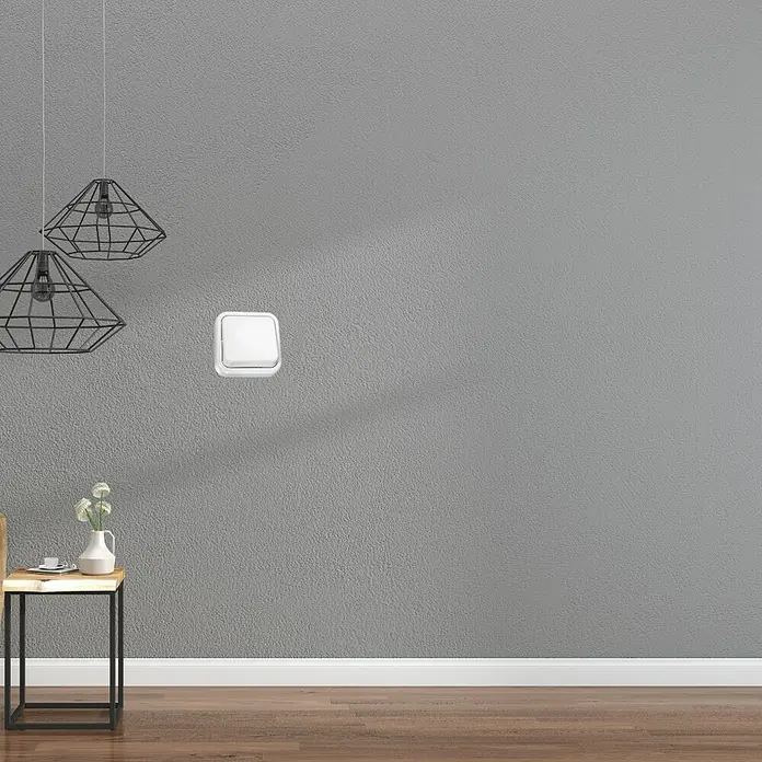 Fontini Kristal Interruptor - Blanco, Colocar, Para interior - La imagen muestra un interruptor de luz blanco en una pared gris, junto a lámparas y una pequeña mesa con decoración.
