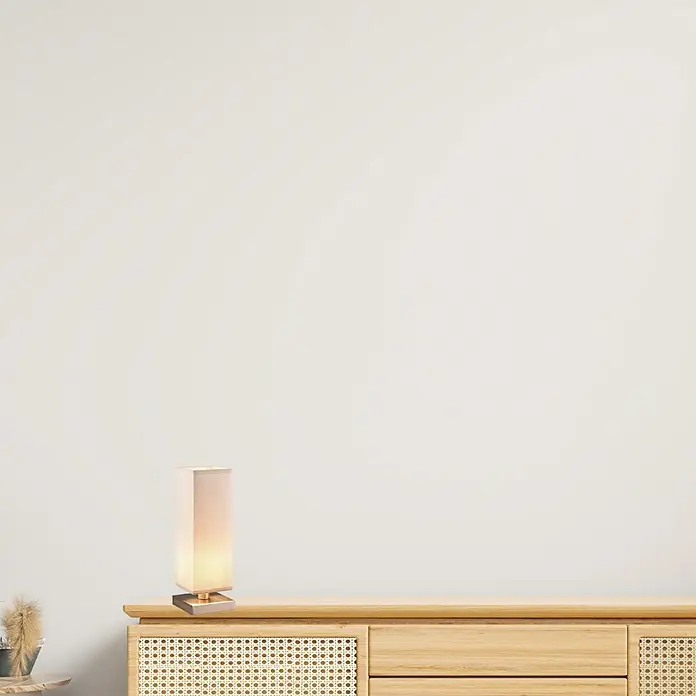 Lámpara de sobremesa decorativa Touch - 60 W, L x An x Al: 12 x 12 x 35,5 cm, Níquel satinado, Gris, E14 - Una elegante lámpara de mesa con pantalla rectangular se encuentra sobre un mueble de madera y emite una luz cálida. La lámpara es un elemento de decoración elegante.