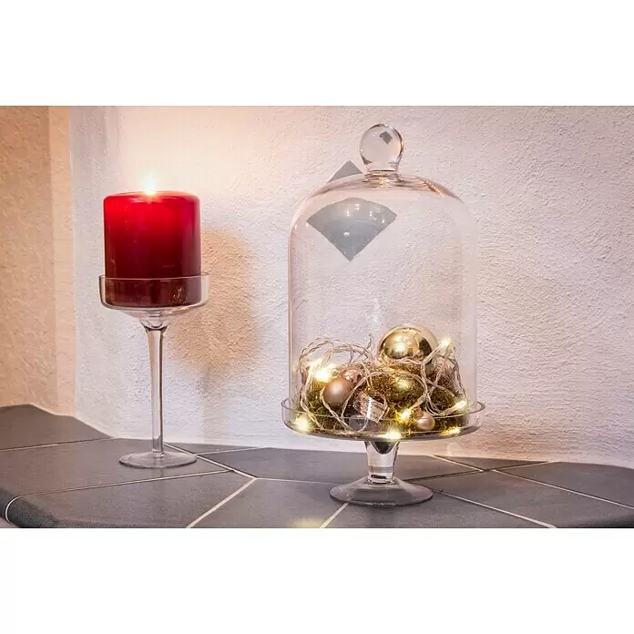 Konstsmide LED-Lichterkette Lichterkette - Innen, Lichtfarbe: Warmweiß, Anzahl Leuchtmittel: 50 Stk., Batteriebetrieben - Eine brennende rote Kerze im Glashalter neben einer Glasglocke mit Moos, Lichterkette und goldenen Kugeln als festliche Dekoration.