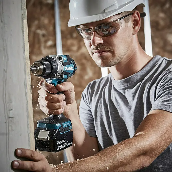 Makita LXT 18V Akku-Schlagbohrschrauber DHP489RTJ - 18 V, 2 Akkus, 5 Ah, 73 Nm - Der Makita Akku-Bohrschrauber im Einsatz: Ein Handwerker bohrt mit dem leistungsstarken Gerät ein Loch in Holz.