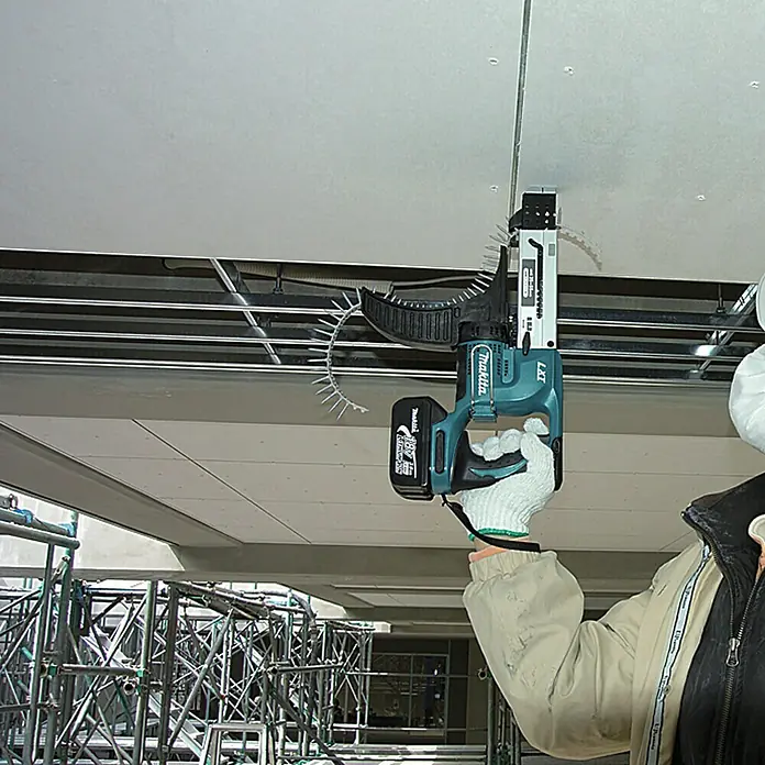 Makita LXT 18V Akku-Trockenbauschrauber mit Magazin DFR550RTJ - 18 V, 2 Akkus, 4.000 U/min, Inkl. Koffer - Ein Arbeiter befestigt eine Decke mit einem Makita LXT Akku-Magazinschrauber, der mit einem Magazin für Schrauben ausgestattet ist.