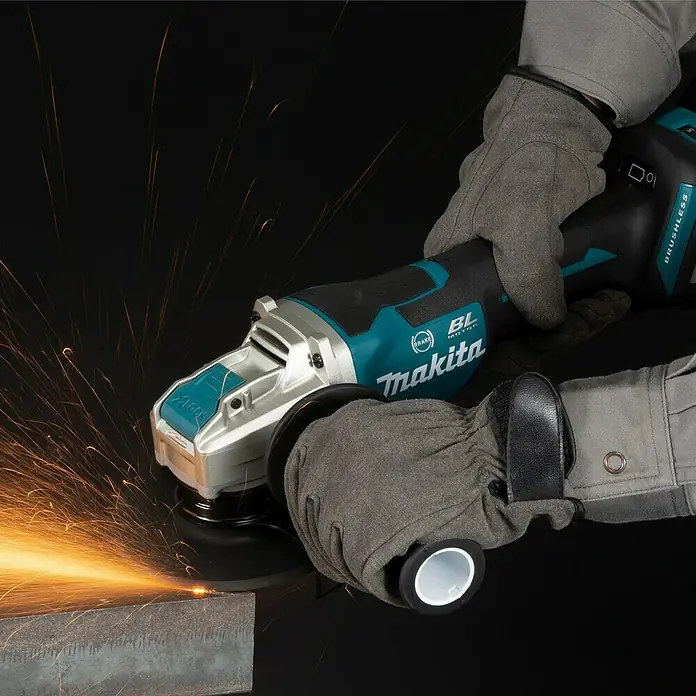 Makita LXT 18V Akku-Winkelschleifer DGA519RTJ - 18 V, 2 Akkus, Durchmesser Scheibe: 125 mm - Nahaufnahme eines Makita Winkelschleifers mit Schutzhandschuhen beim Schneiden von Metall, wobei Funken sprühen.