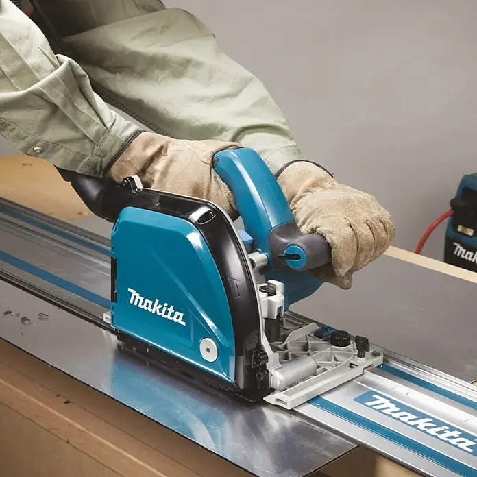 Makita Plattenfräse CA5000XJ - 1.300 W, Leerlaufdrehzahl: 2.200 U/min - 6.400 U/min - Detailaufnahme einer Makita Tauchsäge mit Führungsschiene in Aktion, ideal für präzise Schnitte.