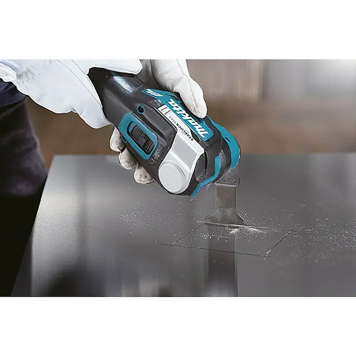 Makita LXT 18V Akku-Multifunktionswerkzeug DTM52T1JX2 - 18 V, 1 Akku - Nahaufnahme einer Makita oszillierenden Multifunktionswerkzeug, das durch eine graue Oberfläche schneidet.