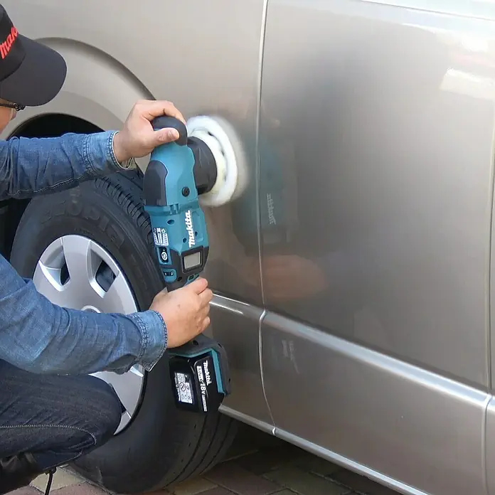 Makita LXT 18V Akku-Exzenterpolierer DPO500Z - 18 V, Ohne Akku - Ein Mann poliert ein Auto mit einer Makita Poliermaschine. Das Gerät ist blaugrün und hat einen Akku.
