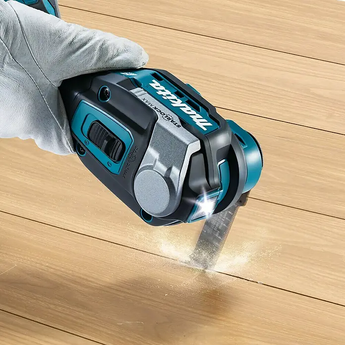 Makita XGT 40V max. Akku-Multifunktionswerkzeug ‎TM001GZ - 40 V, Ohne Akku - Das Bild zeigt einen Makita Multifunktionsschneider in Aktion, der Holz schneidet. Das Werkzeug ist teal und schwarz und wird von einer Hand gehalten.
