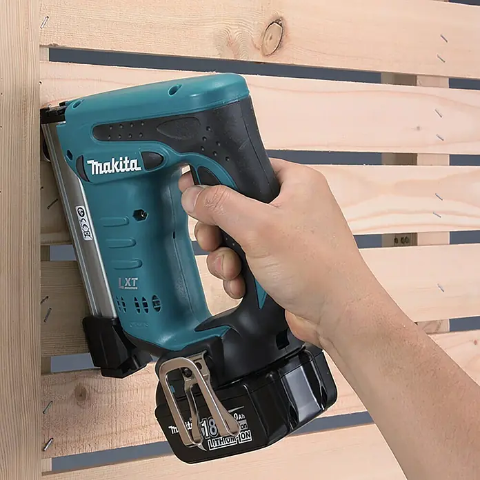 Makita LXT 18V Akku-Tacker DST221RTJ - 18 V, 2 Akkus, 5 Ah - Nahaufnahme eines Makita-Akku-Naglers beim Befestigen von Holzlatten, der für Bau- und Renovierungsarbeiten verwendet wird.