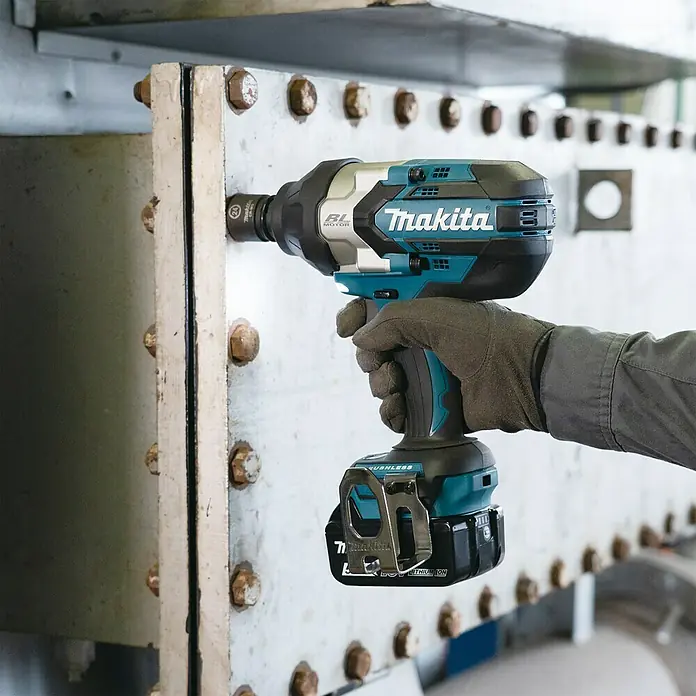 Makita LXT 18V Akku-Schlagschrauber DTW1004Z - 18 V, Ohne Akku, 4 Ah, 1.050 Nm - Nahaufnahme eines Makita Akku-Schlagschraubers mit Akku, der an einer Metallstruktur mit Schrauben befestigt ist.