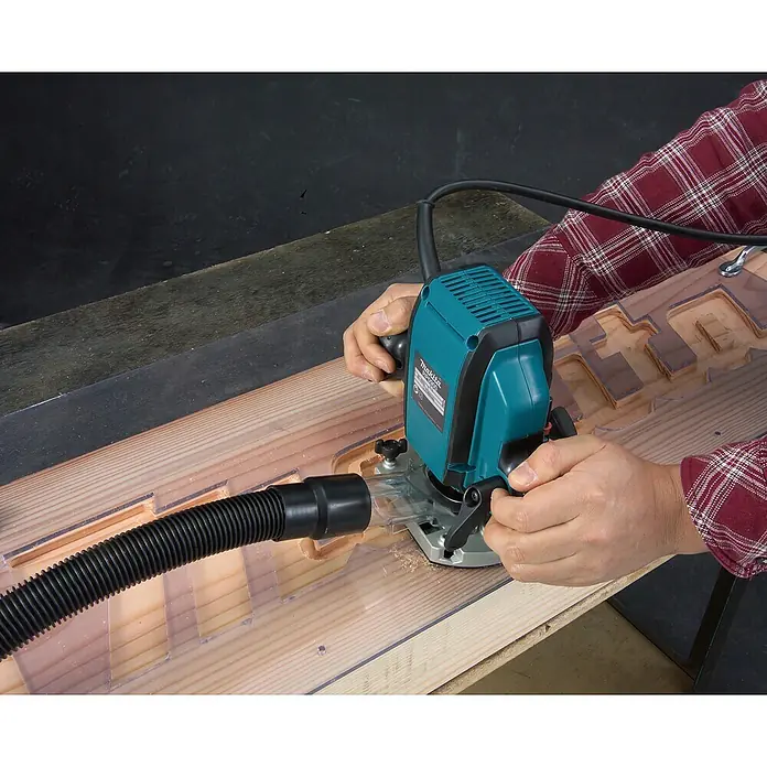 Makita Oberfräse RP0900J - 900 W, 0 U/min - 27.000 U/min, Frästiefe: 35 mm - Der Makita RT0700CX2J Fräsmotor in Aktion, ein Werkzeug für präzise Holzarbeiten mit Staubabsaugung für saubere Arbeitsumgebung.