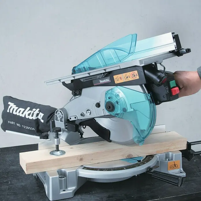 Makita Kapp- & Gehrungssäge LH1040F - 1.650 W, Durchmesser Sägeblatt: 260 mm, Leerlaufdrehzahl: 0 U/min - 4.800 U/min - Detailaufnahme einer Makita Kapp- und Gehrungssäge mit Holzstück, das für einen präzisen Schnitt vorbereitet wird.