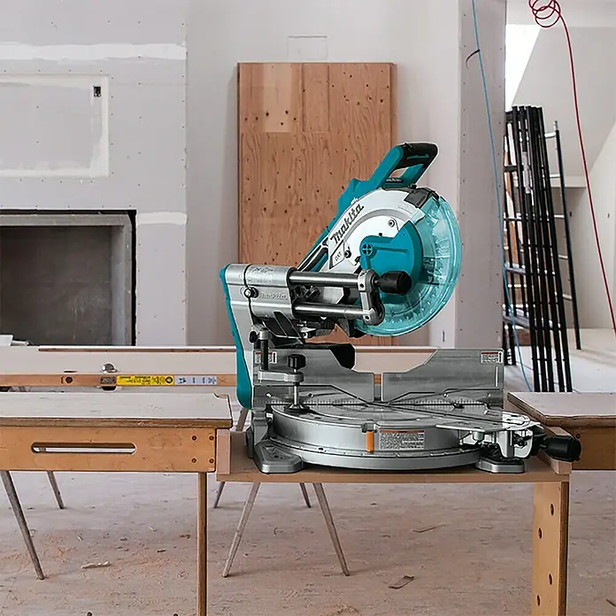 Makita LXT 18V Akku-Kapp- & Gehrungssäge DLS211ZU - 36 V, Ohne Akku - Makita Kapp- und Gehrungssäge auf einer Werkbank in einer unfertigen Baustelle. Präzise Schnitte für Profis.