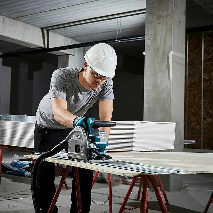 Makita XGT 40V max. Akku-Tauchsäge im MAKPAC SP001GZ03 - 40 V, Ohne Akku, Durchmesser Sägeblatt: 165 mm, 2.500 U/min - Ein Bauarbeiter benutzt eine Makita Tauchsäge mit Führungsschiene, um Gipskarton zu schneiden. Er trägt Schutzkleidung für die Arbeitssicherheit.