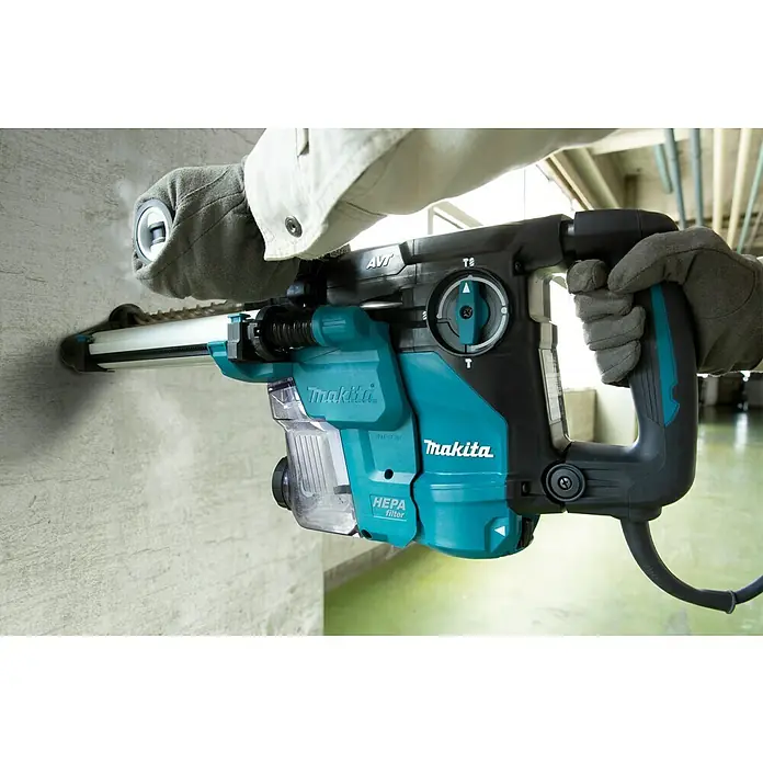 Makita Kombihammer HR3011FCJ - 1.050 W, 3,9 J, SDS-Plus-Aufnahme - Nahaufnahme eines Makita Abbruchhammers in Aktion, der in eine Betonwand bohrt und Staub absaugt.