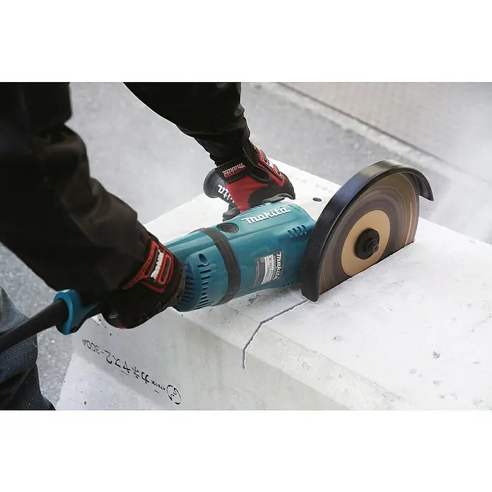 Makita Elektro-Winkelschleifer GA9040RF01 - 2.600 W, Durchmesser Scheibe: 230 mm, Leerlaufdrehzahl: 0 U/min - 6.600 U/min - Detailaufnahme einer Makita-Trennschleifers beim Schneiden von Beton, mit Fokus auf Präzision und Kraft des Werkzeugs.