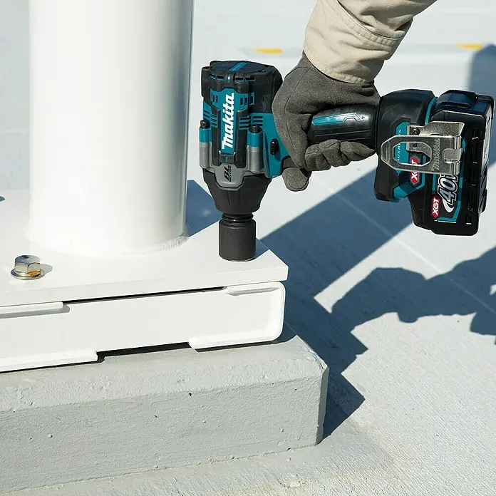Makita XGT 40V max. Akku-Schlagschrauber TW007GZ - 40 V, 760 Nm - Nahaufnahme eines Makita-Schlagschraubers mit Akku in Aktion, bedient von einer Person mit Handschuhen, im Freien.