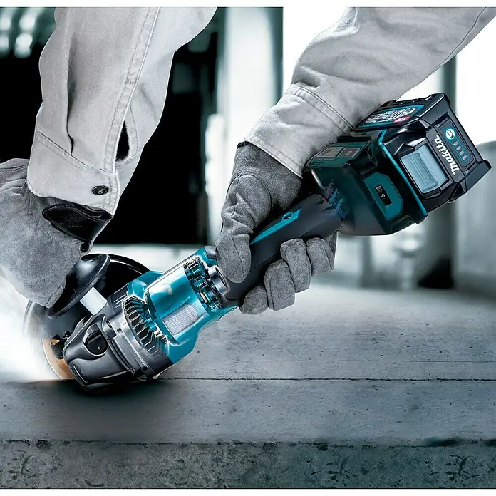 Makita XGT 40V max. Akku-Winkelschleifer GA023GZ - 40 V, Ohne Akku - Eine Nahaufnahme eines Makita Akku-Winkelschleifers in Aktion, der Funken sprüht, gehalten von einer Person mit Handschuhen.