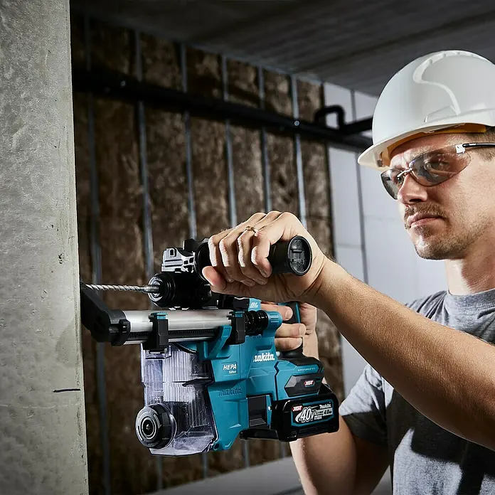 Makita XGT 40V max. Akku-Kombihammer HR010GZ - 40 V, Ohne Akku, 2,1 J - Ein Bauarbeiter benutzt eine Makita Akku-Bohrhammer mit Staubabsaugung. Das Gerät ist blaugrün und schwarz und wird mit einem 40V Akku betrieben.