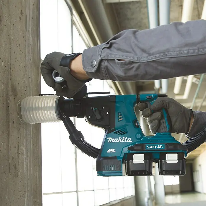 Makita LXT 18V Akku-Kombihammer für SDS-PLUS DHR280ZJ - 36 V, Ohne Akku, Max. Einzelschlagenergie: 2,8 J - Akkubohrhammer von Makita in Aktion, der in eine Betonwand bohrt. Das Gerät ist blaugrün und verfügt über zwei Akkus für eine lange Laufzeit.