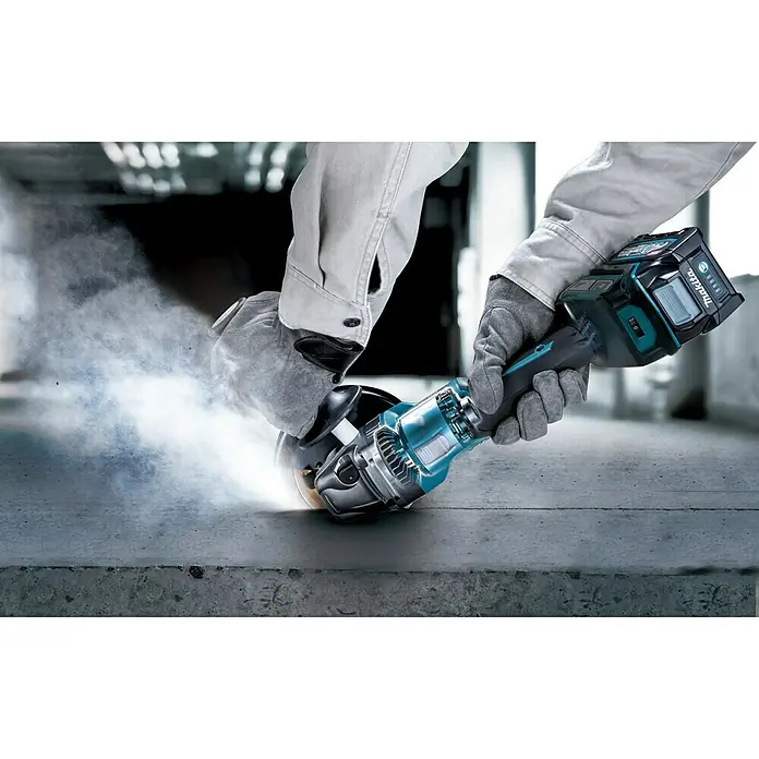 Makita XGT 40V max. Akku-Winkelschleifer GA023GZ - 40 V, Ohne Akku - Nahaufnahme eines Akku-Winkelschleifers von Makita in Aktion, der Funken sprüht und Staub aufwirbelt. Ideal für Bau- und Renovierungsarbeiten.