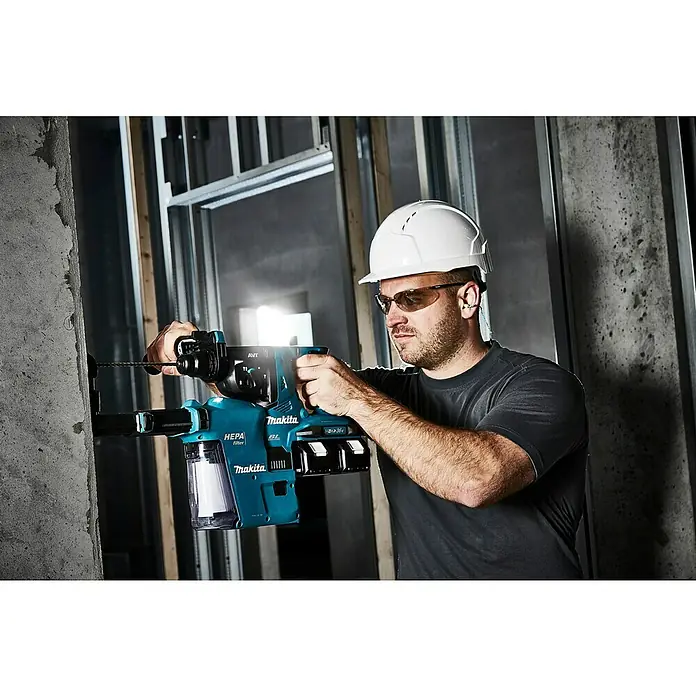 Makita LXT 18V Akku-Kombihammer für SDS-PLUS DHR280ZJ - 36 V, Ohne Akku, Max. Einzelschlagenergie: 2,8 J - Ein Bauarbeiter bohrt mit einer Makita HEPA Filter Bohrmaschine ein Loch in eine Betonwand. Er trägt dabei einen Helm und eine Schutzbrille.