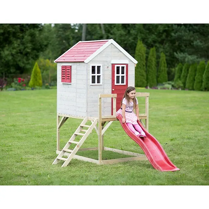Wendi Toys Spielhaus Tiger - Glas, Natur/Rot - Mädchen auf einer roten Rutsche an einem Spielhaus mit rotem Dach. Das Spielhaus steht auf einem grünen Rasen vor Bäumen.