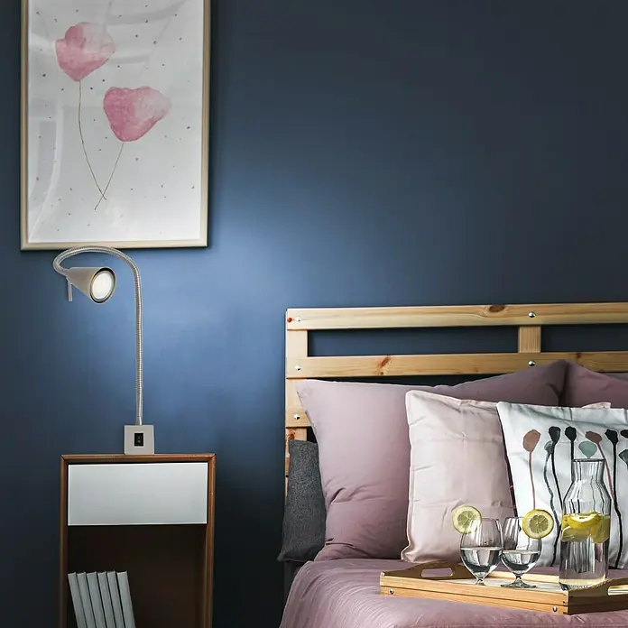 Briloner LED-Wandstrahler Tuso - 4 W, L x B x H: 5,8 x 21,7 x 40,3 cm, Warmweiß - Ein Schlafzimmer mit einem Nachttisch, einer Lampe, einem Bett mit Kissen und einer Karaffe Wasser.